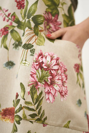 Floral print apron with pink flowers and green leaves on beige cotton fabric, featuring front pocket
