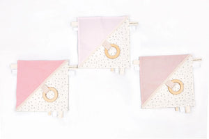 Set de tres doudous para bebé en rosa pastel y crema con patrones de estrellas y aros de dentición de madera.