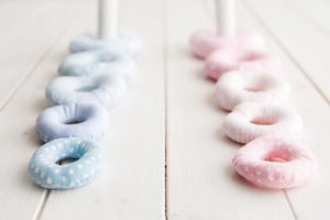 Soft fabric stacking rings in pastel blue and pink, polka dot and striped patterns, on wood