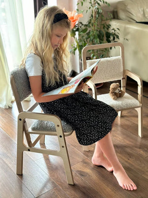 Child reading on light wood chair with gray wool cushion, nursery decor, European handmade