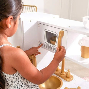 Gros plan sur une jeune fille appuyant sur les boutons interactifs du micro-ondes de la cuisine Angelove lors d'un jeu imaginatif.