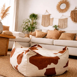 Pouf carré à motif vache pour enfant dans un salon neutre à la déco bohème