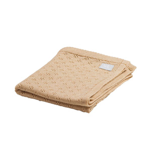 Couverture bébé en tricot ajouré beige en coton doux, pliée sur fond blanc