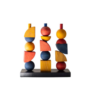 Colorful wooden geometric sculpture with stacked spheres, cubes, and wedges on black base