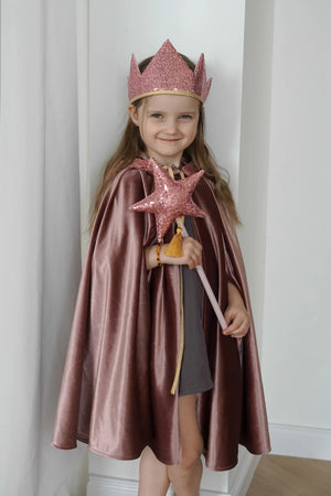 Child wearing the Cosmic Pearl magic cape with a pink crown and star wand during indoor dress-up play