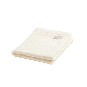 Couverture bébé en tricot crème en coton bio avec motif subtil, pliée sur fond blanc