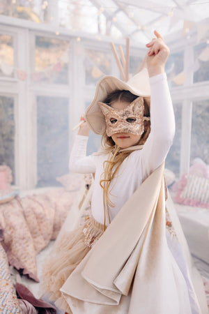 Child wearing a Cream Pearl hooded cape with a sequined cat mask during indoor dress-up play
