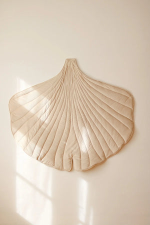 Close lifestyle view of cream quilted Ginkgo Leaf Mat displayed on a softly lit wall
