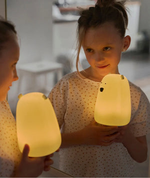 Enfant tenant une veilleuse ourson jaune pour enfant devant un miroir