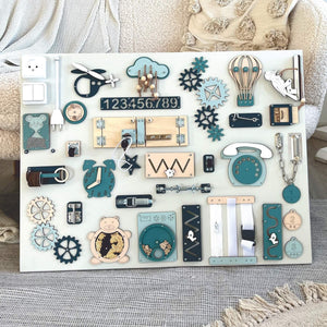 Wooden Montessori busy board with teal, navy, and natural wood elements, featuring gears, latches, zippers, and number tiles for toddler fine motor skills.