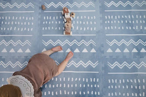 Tapis de jeu puzzle en mousse boho azur avec motif géométrique blanc dans une chambre d'enfant
