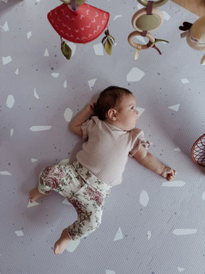 Bébé allongé sur un tapis de jeu puzzle en mousse lavande à motif terrazzo, décoration de chambre