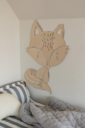 Decorazione da parete in legno a forma di volpe in una tonalità neutra sopra il letto di un bambino