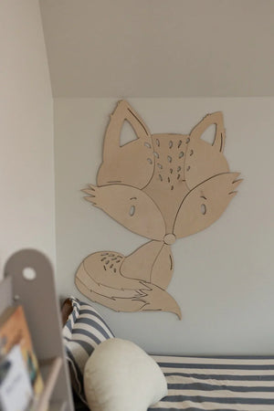 Decorazione da parete in legno a forma di volpe in una stanza per bambini minimalista sopra biancheria da letto a righe