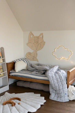 Decorazione da parete in legno a forma di volpe in una cameretta moderna sopra un letto a righe