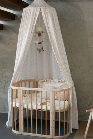 Gold Dust nursery mobile displayed beneath a floral canopy above a natural wooden cot