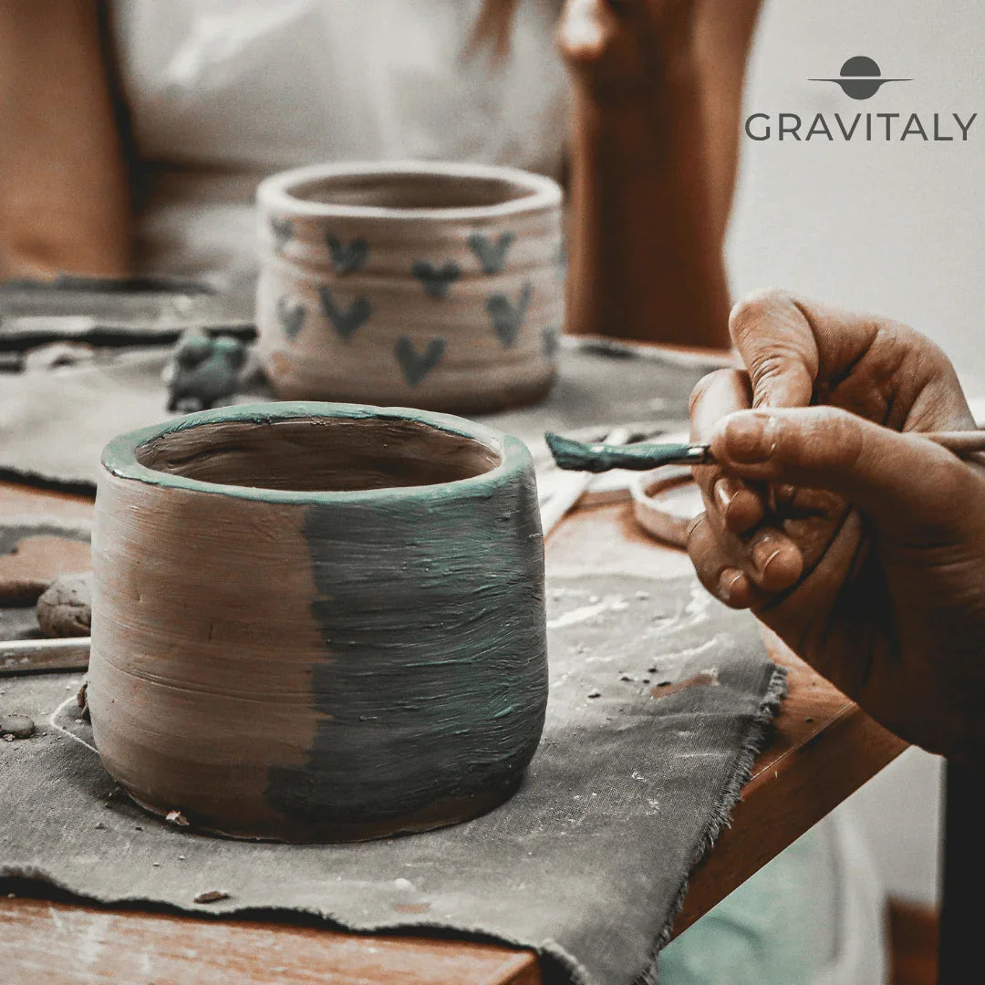 handmade clay pottery being hand-painted with green glaze in an artisan workshop