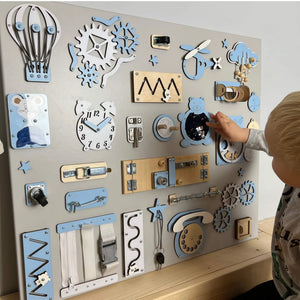 Blue and white wooden toddler activity board with gears, latches, clock, and sensory toys for nursery development