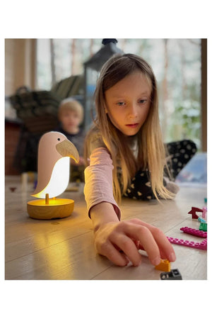 Enfants jouant près d'une veilleuse oiseau avec socle en bois diffusant une lumière douce et chaude