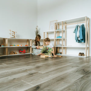 Children playing beside One Little Pine modular shelves, wardrobe and low Montessori storage furniture