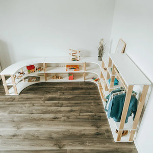 Overhead view of a children’s room arranged with curved Montessori shelves and modular wardrobe storage