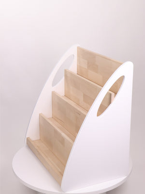 Empty four-level Montessori bookshelf in white and natural birch wood shown from a three-quarter front angle