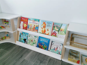 Two-shelf front-facing Montessori bookcase positioned between curved and straight modular storage units
