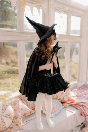 Child wearing black Moi Mili magic cape, pointed witch hat and star wand during fantasy dress-up play