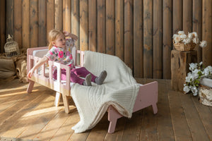 Child sitting on pink extendable FAMILY kids bed in cosy sofa-style configuration