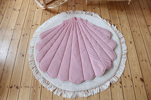 Powder pink Moi Mili shell playmat displayed on a round cream rug over natural wooden flooring