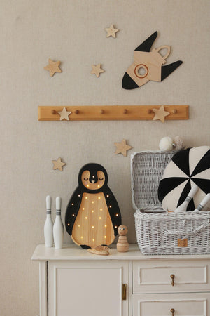 Wooden penguin night light with warm LED dots, stars, and rocket wall decor for nursery