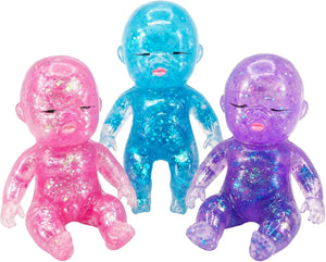 Three glittery translucent baby-shaped squishy toys in pink, blue, and purple