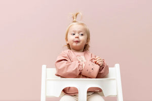 Kleinkind im wasserdichten Langarm-Lätzchen in Blush Pink mit Katzen-Print im Hochstuhl
