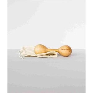 Wooden baby rattle with natural finish, engraved 'WOODEN STORY', resting on cream drawstring bag