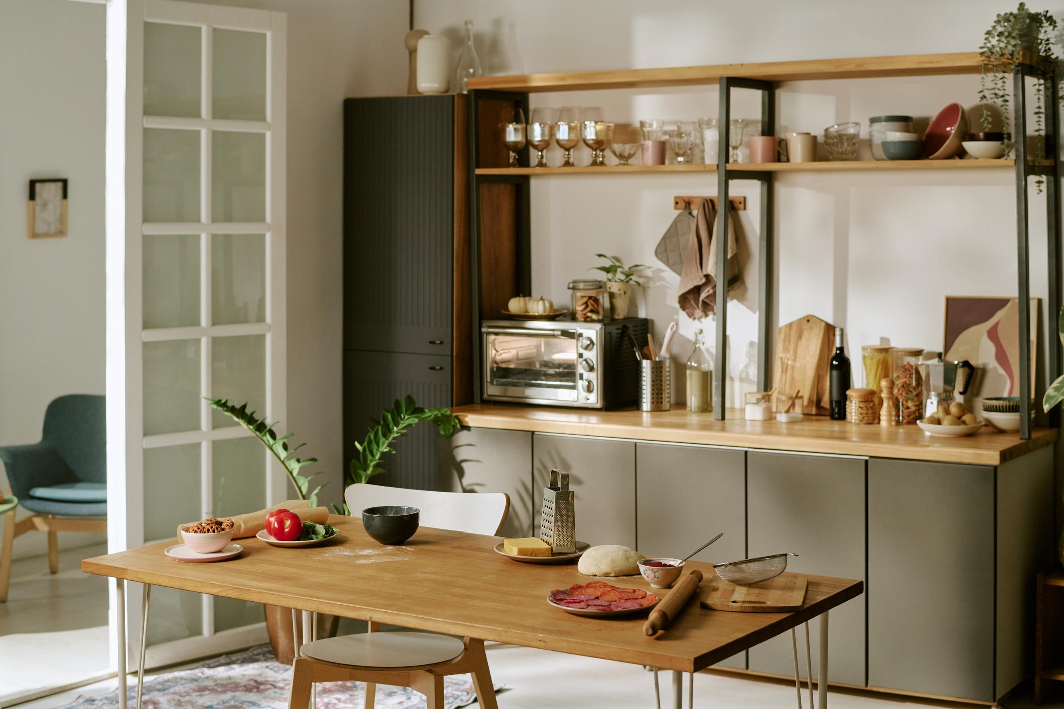 Cucina moderna con tavolo da pranzo, tazze, ciotole e accessori della collezione Gravitaly.