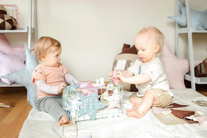 Dos niños pequeños jugando con almohadas de estrellas de tela pastel y una cesta de almacenamiento en la guardería.
