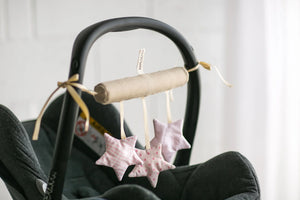 Soft fabric star-shaped stroller toy in pastel pink patterns attached to a car seat handle