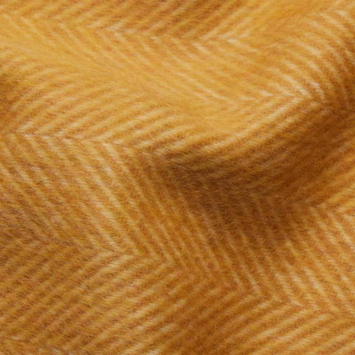 Gros plan sur la texture douce d'un jeté en laine d'alpaga jaune moutarde