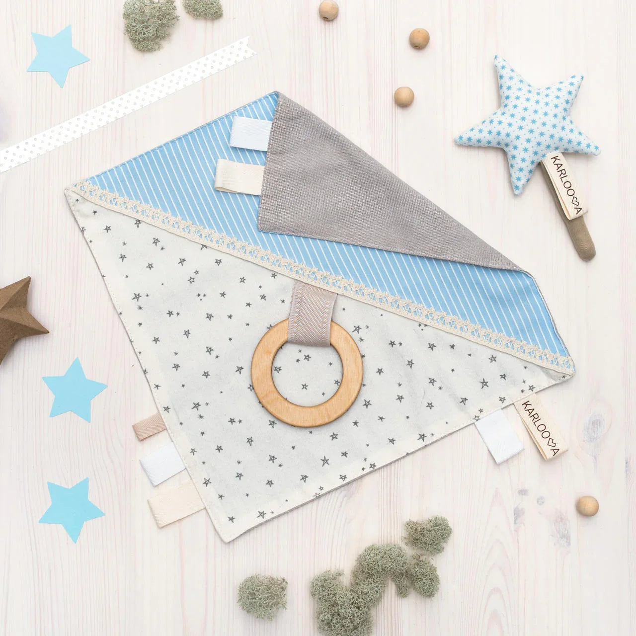 Baby sensory comforter with blue and grey fabric, star pattern, wooden teething ring, and fabric tags