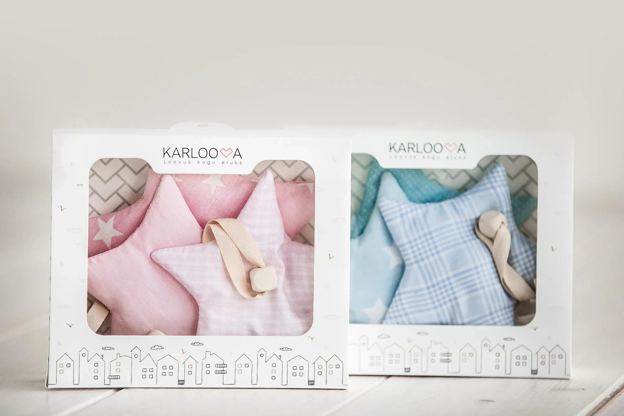 Sets de decoración infantil de estrellas de tela en rosa y azul, presentados en cajas de regalo con patrones y lazos para colgar.
