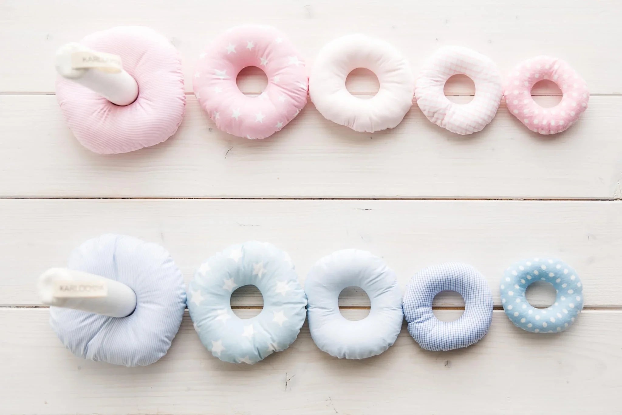 Pink and blue soft fabric stacking rings in assorted patterns on white wood nursery decor