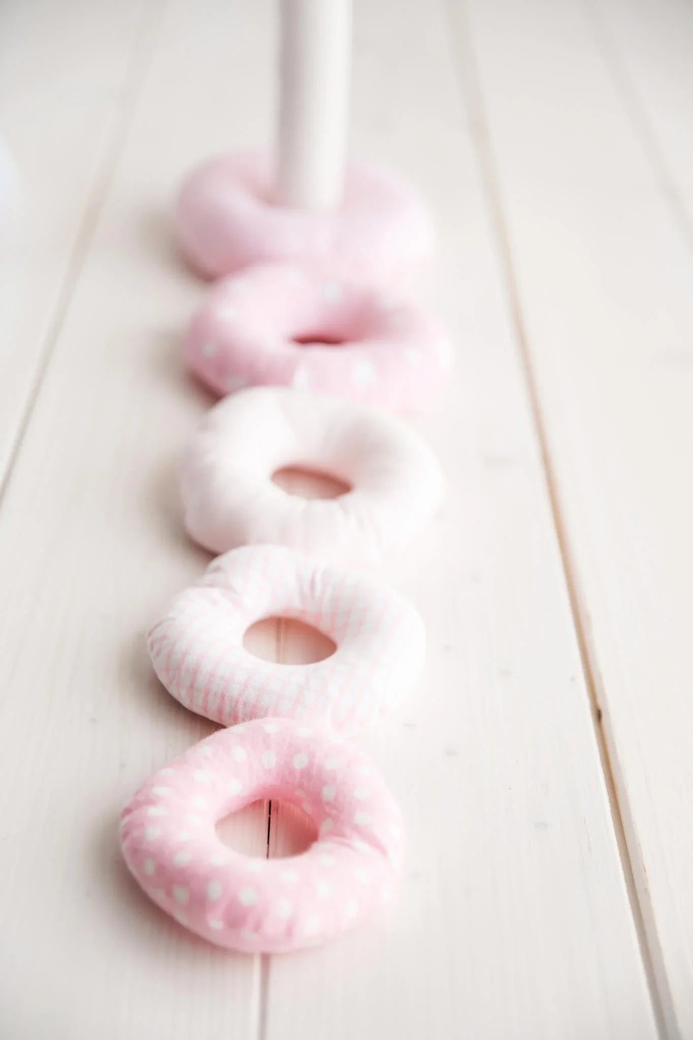 soft pink and white fabric stacking rings on light wood nursery floor