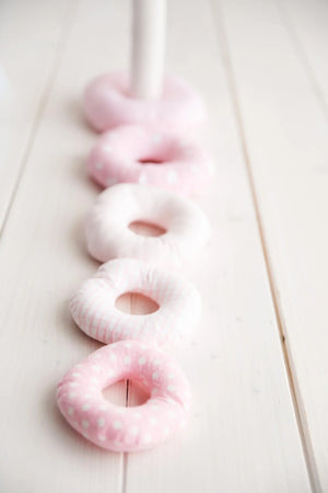 soft pink and white fabric stacking rings on light wood nursery floor