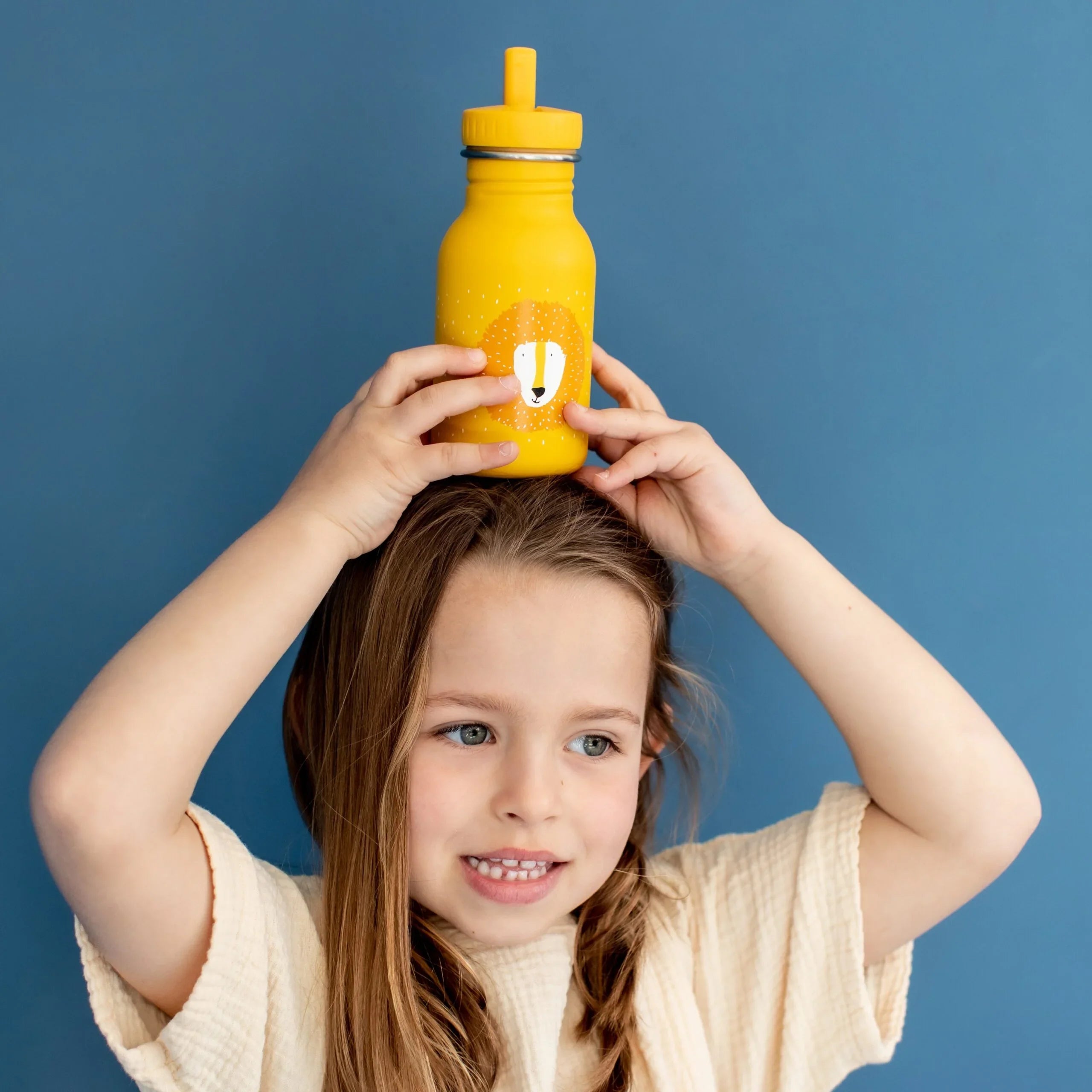 Niño sujetando una botella de agua de acero inoxidable amarilla con estampado de león y tapa con pajita