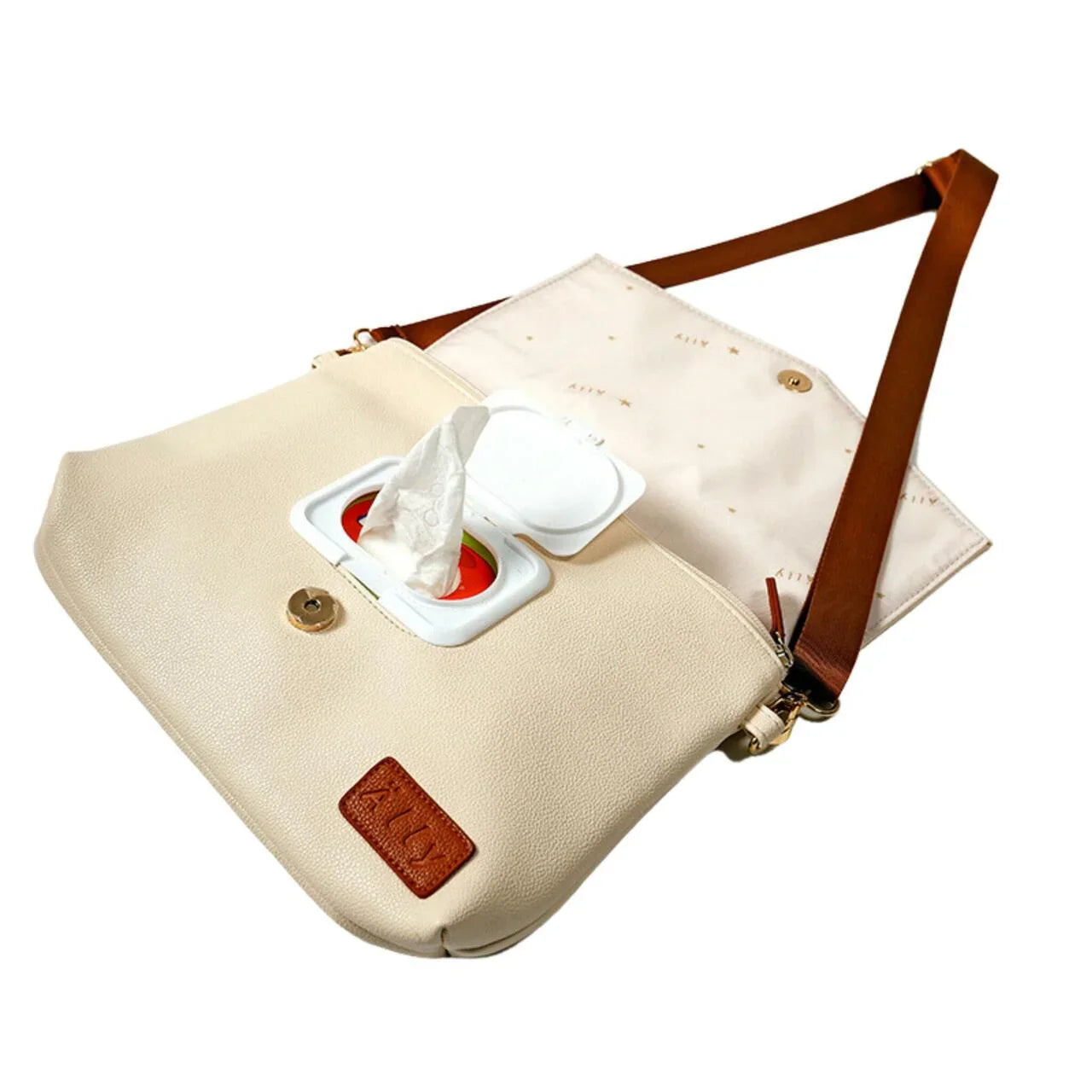 Schräge Ansicht der offenen hellcremefarbenen Älly Cappuccino Wickeltasche: ein Feuchttuch wird aus dem praktischen integrierten Spender gezogen.