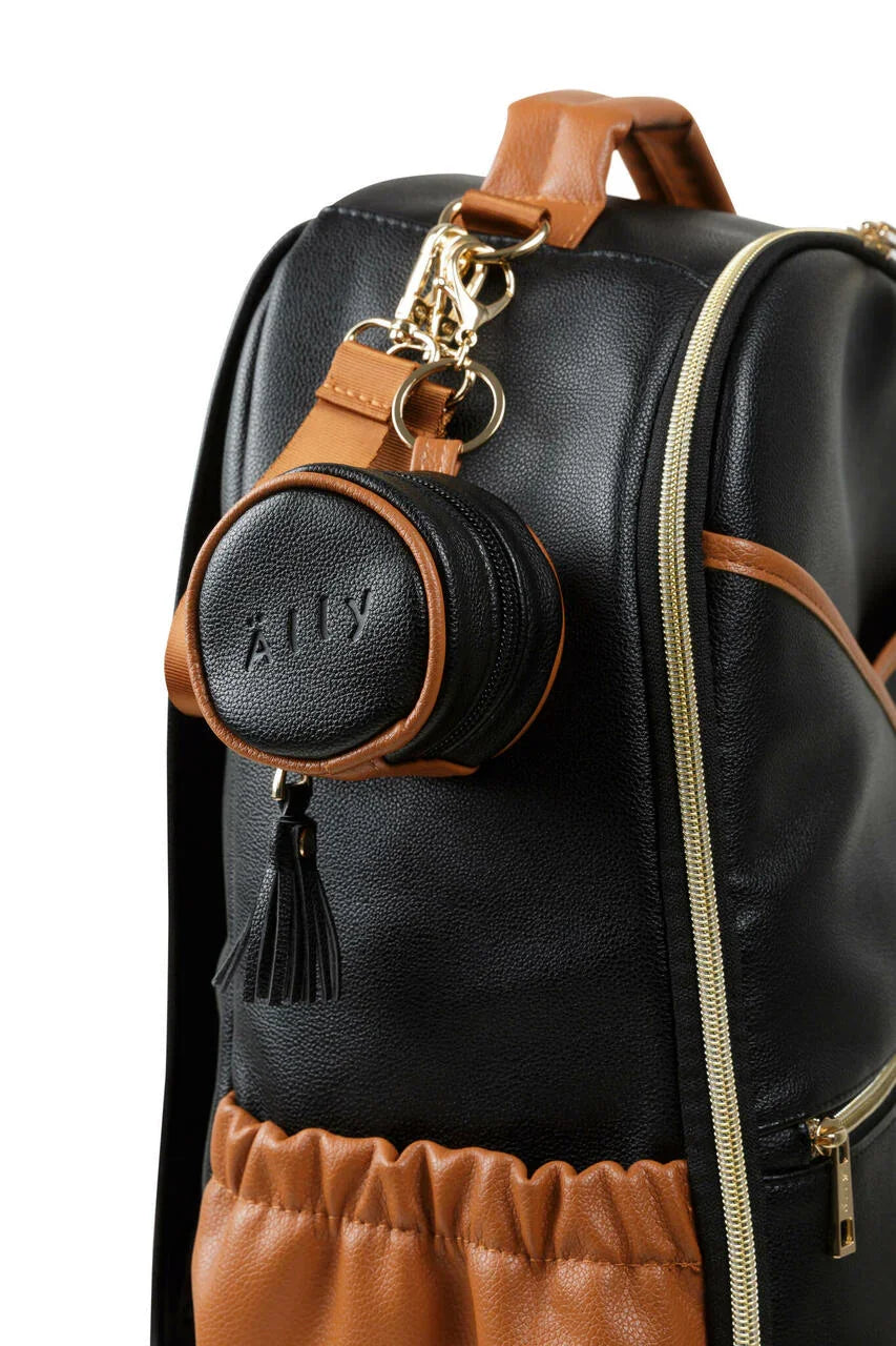 Étui à tétine en cuir noir et tanné avec fermeture éclair, attaché à un sac à langer avec détails dorés