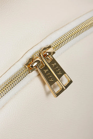 Dettaglio delle cerniere YKK dorate premium con logo personalizzato Ally Scandic sulla borsa fasciatoio in similpelle bianca.
