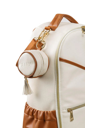 Étui à tétine en cuir beige et tanné avec pompon, attaché à un sac à langer assorti