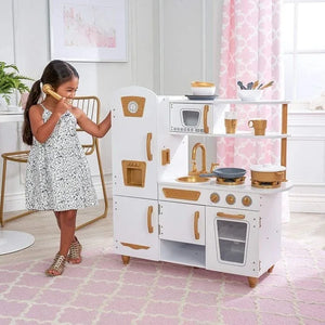 Photo lifestyle d'une jeune fille jouant avec la cuisine Angelove haut de gamme, tenant un téléphone jouet à côté du réfrigérateur.