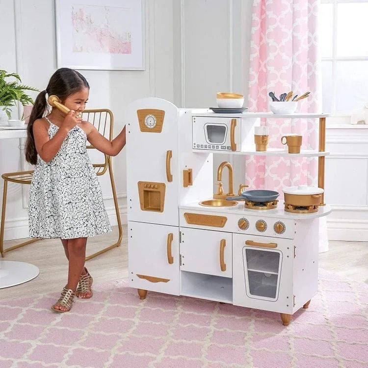 Niña jugando a "cocinar" con la cocina de madera Angelove, sosteniendo el teléfono de juguete junto a la nevera